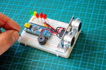 Glowing light emitting diode in short LED which is an Electronic component connected to breadboard with some micro controller on background. Robotic coding