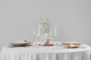 Served restaurant table with flowers in vase on light background