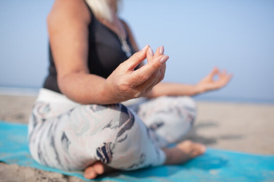 Middle-aged woman does yoga on the shore of the Indian Ocean early in the morning