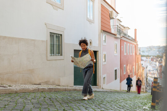 Young tourist woman walking in lisbon reading a map