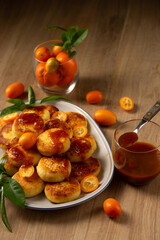 Delicious pancakes with cottage cheese, kumquat jam and fruits on a table