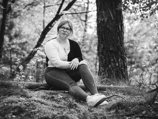 Young thoughtful woman sitting on a fallen tree

