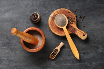 Mortar and wooden spoon of black pepper powder with peppercorns on dark background
