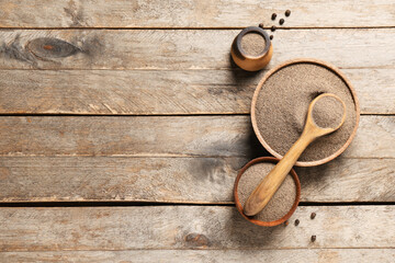Bowls and spoon of black pepper powder with peppercorns on wooden background