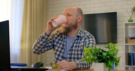 Bald man working at desk embraces comfort in home office, comfort fueling creative focus while comfort eases tension, supporting daily productivity. Remote work of man at computer