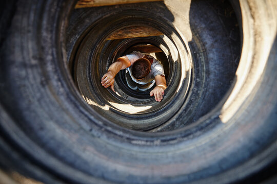 Athlete, man and crawl with obstacle outdoor for strength training, military practice and mobility. Above, person and tire course for exercise challenge, fitness workout and survival test at bootcamp