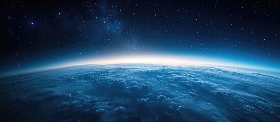 Fototapeta premium Vast view of Earth from space showcasing blue planet's curvature against dark starry background with a soft glow at the horizon.