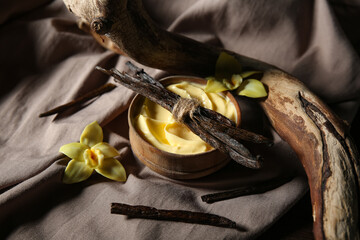 Composition with bowl of tasty pudding, vanilla sticks, tree branch and fabric