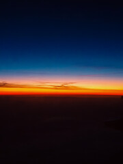 A breathtaking sunrise above the clouds, painting the sky with warm hues of orange, pink, and deep blue
