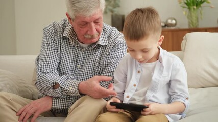 Happy family at home. Old senior man grandfather boy grandson enjoying time together watching video on phone. Good time at home. grandparent and child together. Older generation modern tech usage