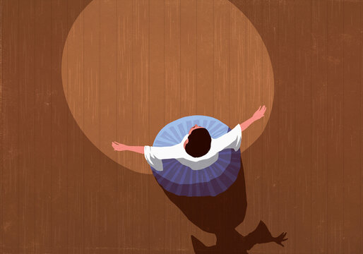 View from above opera singer with arms outstretched performing on stage in spotlight
