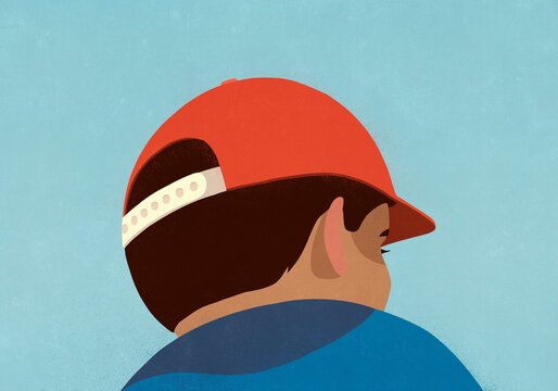 Low angle view brunette boy in red baseball cap looking away
