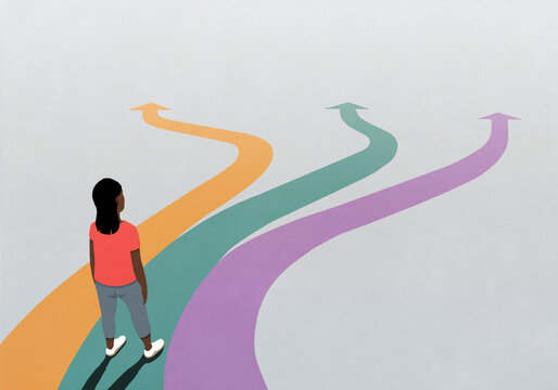 Woman looking down at multicolored arrow paths extending in front of her
