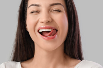 Young woman with healthy teeth smiling on light background, closeup