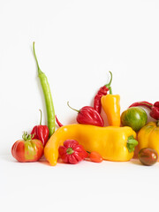 pile of tomatoes and different peppers isolated on white background. Stacked vegetables