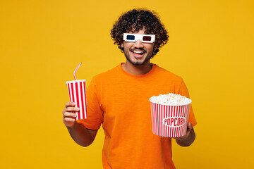 Young smiling happy Indian man he wear orange t-shirt casual clothes 3d glasses watch movie film...