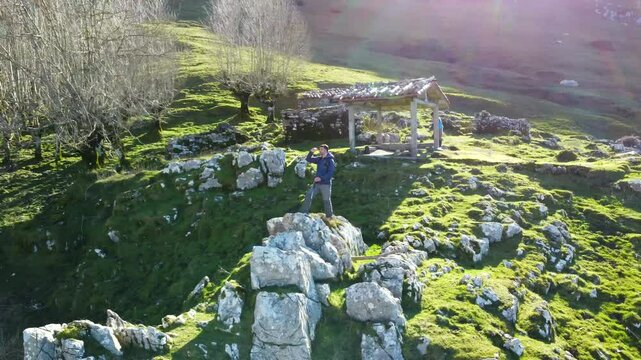 Adventurous hiker contemplating scenic views from limestone rock formation in mount txindoki, basque country. Green slopes and mountainous landscape surrounding