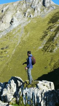 Experienced male hiker standing on mount txindoki's summit, contemplating expansive landscape of gipuzkoa's verdant basque mountain terrain under bright sunlight