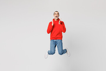 Full body young surprised shocked middle eastern man he wears red hoody casual clothes jump high spread hands look camera isolated on plain solid white background studio portrait. Lifestyle concept.