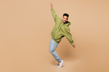 Full body young man of African American ethnicity wears green hoodie casual clothes standing on...