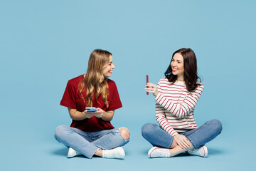 Full body young couple two friends women wear red casual clothes together sit hold in hand use...