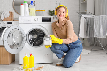 Young woman with headphones and baking soda cleaning washing machine in laundry room