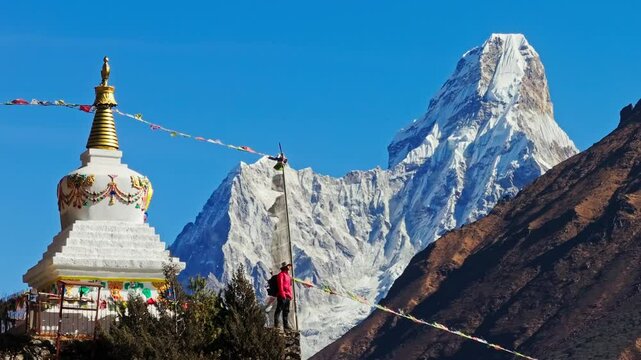 Aerial view of mountaineer standing near Buddhist stupa with Ama Dablam peak towering behind, capturing dramatic Himalayan landscape in Nepal