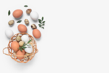 Wicker basket with Easter eggs and leaves on white background