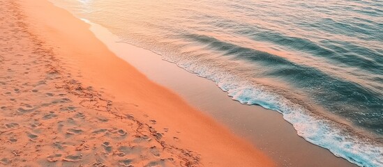 Sunset beach waves wash ashore, leaving footprints in the sand. Vacation use