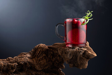 Hot drink with cranberries, lime, and rosemary on a old wooden snag.