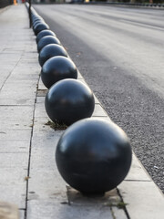 Black spherical bollards lining the pavement on a quiet street in Bucharest, Romania, showcasing urban design and city planning on a calm day