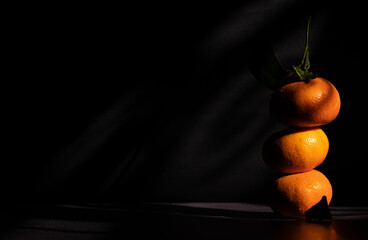 Fresh mandarins stacked on a dark background receiving the morning sun through the window. Dark food