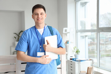 Male medical intern with laptop in clinic