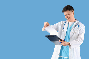 Male medical intern with clipboard on blue background