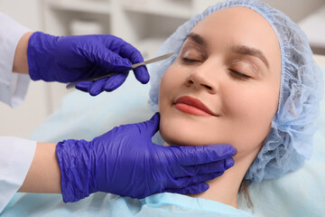 Young woman and plastic surgeon with scalpel in clinic, closeup. Blepharoplasty concept