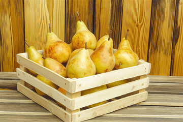 A rustic wooden crate filled with ripe pears, placed on a wooden surface. This image evokes a feeling of farm freshness and natural food, ideal for healthy eating and rustic lifestyle themes.