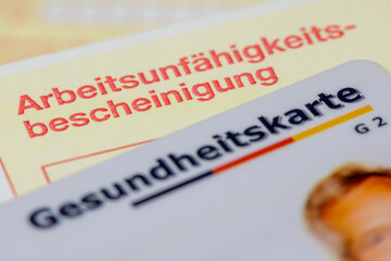 Eine Gesundheitskarte  der Krankenkasse und Arbeitsunfähigkeitsbescheinigung liegen zusammen