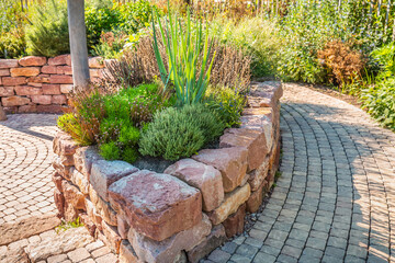 A modern vegetable garden with raised bricks beds. Raised beds gardening in urban garden growing plants and vegetables