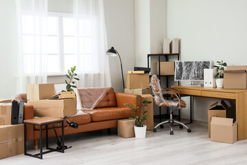 Brown sofa with workplace and cardboard boxes in office on moving day