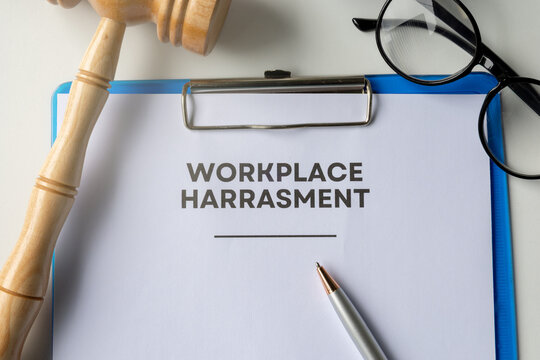 A neatly arranged clipboard with documents labeled "Workplace Harassment" resting on an office table. 