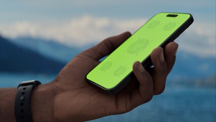 GREEN SCREEN CHROMA KEY A hand holding a smartphone with a green screen on Lake Como during the day, showing a beautiful scenic view. Ideal for travel or tourism apps