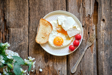 fried egg on a plate with cheese, tomatoes and bread.