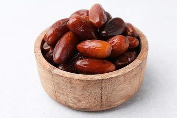 Tasty dried dates in wooden bowl on white table, closeup