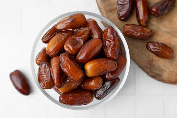 Tasty dried dates in glass bowl on white table, top view