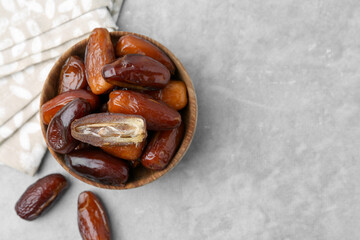 Tasty dried dates in bowl on light grey table, top view. Space for text