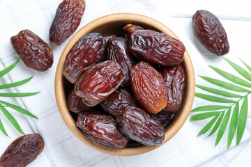 Tasty dried dates and leaves on white table, flat lay