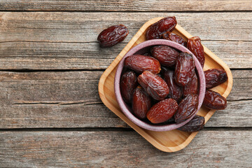 Many tasty dried dates in bowl on table, top view. Space for text