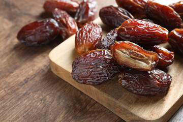 Many tasty dried dates on wooden table, closeup