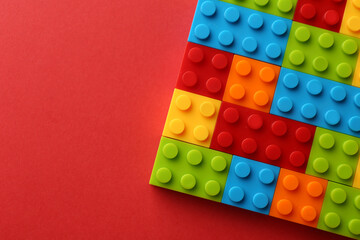 Construction toy. Colorful building bricks on red background, top view with space for text