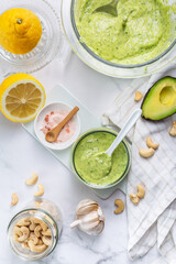 Homemade avocado yogurt dressing with ingredients on kitchen table